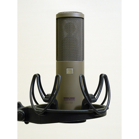 This is a photo of the Sanken CU-51. It is shown in a grey colour, in a front facing view. It is held in place by a black piece of equipment.