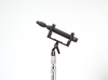 This is a photo of the CO-100K Sanken microphone. The microphone is black and on a side facing view. Held up with a seperate piece of equipment that is black and silver in colour. It is on a white background.