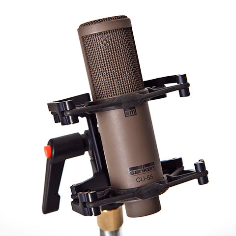 This is a photo of the Sanken CU-55 microphone. It is shown in a brown/grey colour. It is held in place by a piece of black equipment at an angled front view.