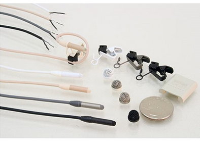 This is a photo of all four colours of the Sanken COS-11D PT/RM microphone. Black, grey, white and beige. Also shown with accessories including microphone clips and microphone wind protectors